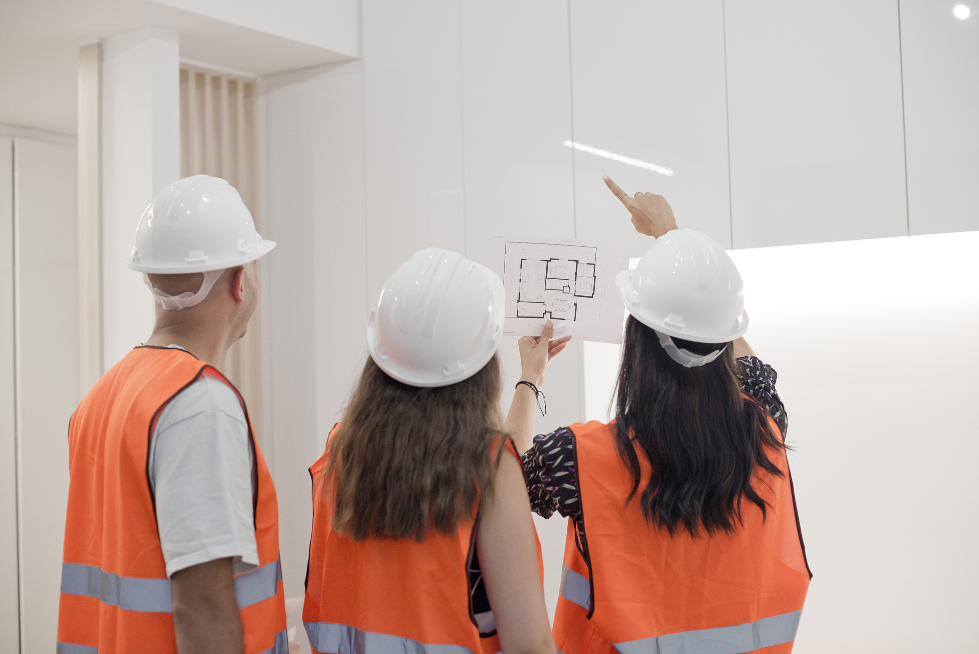 a group of people wearing helmets and vests looking at a blueprint